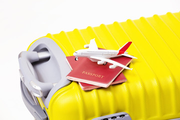 Airplane toy with two passports and fly documents on a yellow suitcase. Travel and airport customs concept