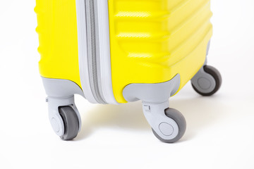 Closeup wheel detail of a modern yellow travel suitcase