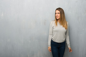 Fototapeta premium Young woman on textured wall is a little bit nervous and scared pressing the teeth