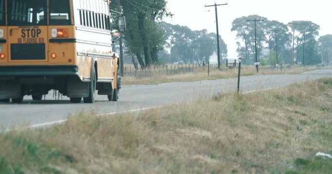 School Bus Driving Down Rural Two Lane Road In America