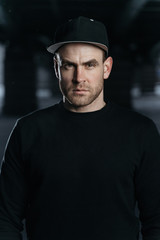 Portrait of man. He is wearing a black sweatshirt and cap. Copy space for your advertising