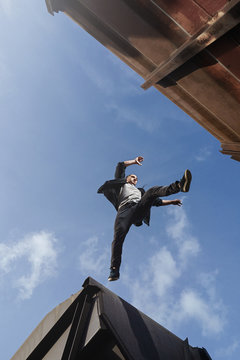 Man doing scary jump between roofs. Guy practicing parkour freerunning.
