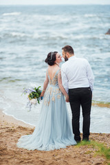 same couple with a bride in a blue dress walk