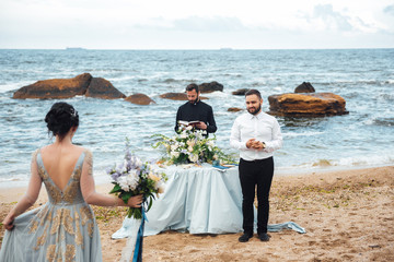 wedding couple on the ocean with a priest