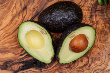 Fresh Organic Avocado cut in half arranged on natural olive wood. Persea americana in the Lauraceae family. Avocado Pear. Alligator Pear.