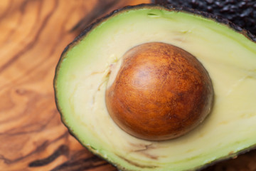 Fresh Organic Avocado cut in half arranged on natural olive wood. Persea americana in the Lauraceae family. Avocado Pear. Alligator Pear.