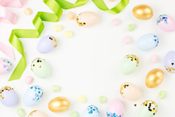 Festive Happy Easter background with decorated eggs, flowers, candy and ribbons in pastel colors on white. Copy space