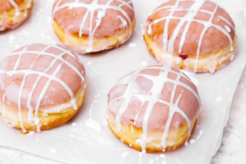 Obraz na płótnie Canvas Traditional Polish donuts with white frosting on white background. Tasty doughnuts with jam.