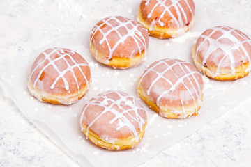 Traditional Polish donuts with white frosting on wooden background. Tasty doughnuts with jam.