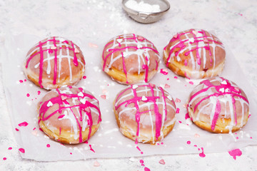 Fototapeta na wymiar Traditional Polish donuts with pink frosting and heart sprinkles on light background. Tasty doughnuts with jam.