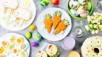 Fototapeta na wymiar Funny colorful Easter food for kids with decorations on table. Easter dinner concept
