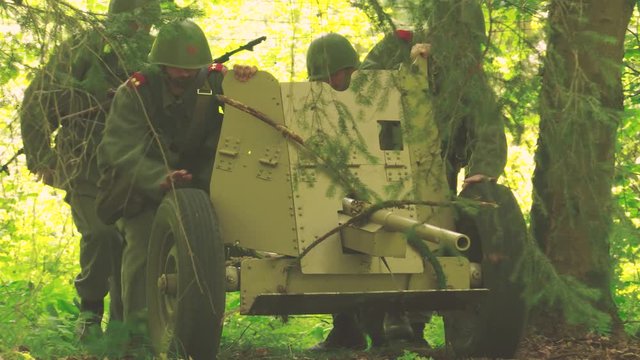 Soldiers moving a anti tank gun in a forest