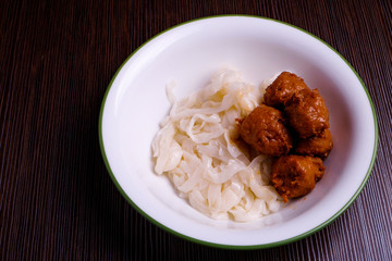Kuey teow and meatballs  in a white bowl on the table