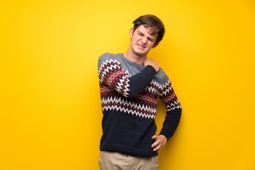 Fototapeta premium Teenager man over yellow wall suffering from pain in shoulder for having made an effort