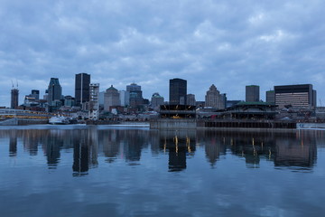 Fototapeta na wymiar Montreal downtown skyline reflected in the St. Lawrence river at the early morning blue hour with clouds, Quebec, Canada