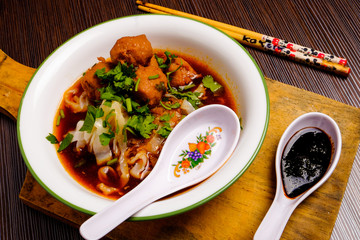 Indonesian famous foodstreet bakso / meatballs in a white bowl served with kuey teow on the table.
