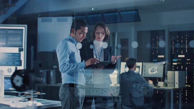 In Technology Research Facility: Female Project Manager Talks With Chief Engineer, they Consult Tablet Computer. Team of Industrial Engineers, Developers Work on Engine Design Using Computers