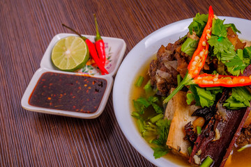 Cow bone soup or Sup Tulang in Malay with chilli and soya sauce . Muslim food in white bowl on dark...