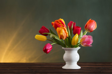 beautiful tulips in vase on green background