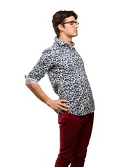 Teenager man with flower shirt and glasses suffering from backache for having made an effort over...