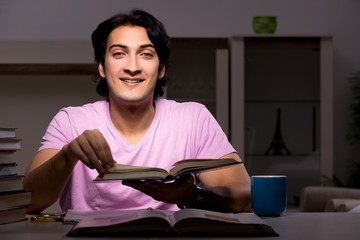 Male handsome student preparing for exams late at home 