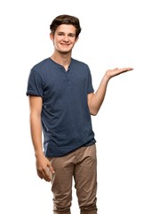 Teenager man holding copyspace imaginary on the palm to insert an ad over isolated white background
