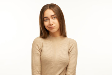 Obraz premium Cute young female dressed casually pursuing lips, absorbed in thinking, trying to find right solution while dealing with some problem, having concentrated indecisive look