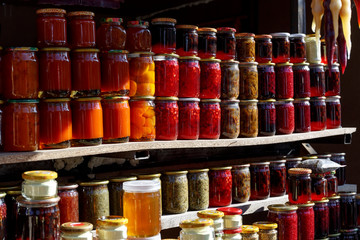 Bright shiny glass jars with homemade canned food stand on the counter in the sun. hand-made food trade in the street market