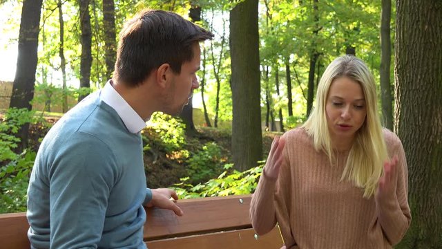 A couple argues on a bench in a park on a sunny day - closeup