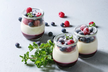 Homemade classic dessert Panna cotta with raspberry and blueberry berries and jelly in jars,...