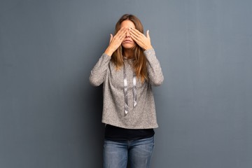 Blonde woman over grey background covering eyes by hands. Do not want to see something