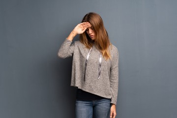 Blonde woman over grey background with tired and sick expression