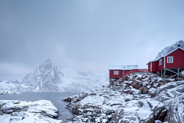 Beautiful traditional fishing red rorbuer huts in Hamnoy village and Olstinden peak. Lofoten...