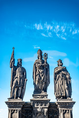 Fototapeta na wymiar Statue of knights and priest at the Charles Bridge in Prague, Czech Republic, summer time, blue sky