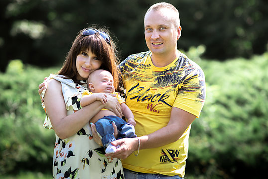 Family of three on a walk, mother holding child, front view