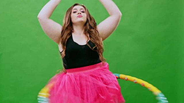 Plump girl in pink skirt twirling hula hoop