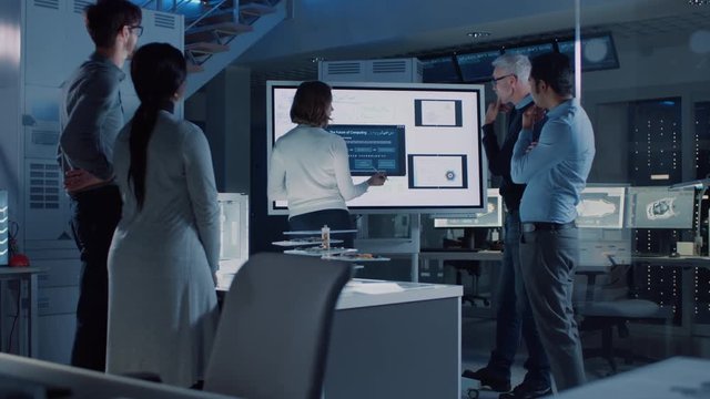 Engineers Meeting in Technology Research Laboratory: Female Engineer Leads Presentation Using Digital Whiteboard, Shows Machine Blueprint, Data Analytics while Colleagues Asking Quiestions