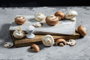 Composition with fresh champignon mushrooms on wooden board. Rustic style