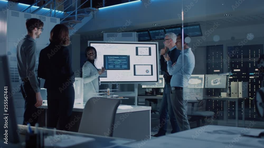 Poster Engineers Meeting in Technology Research Laboratory: Male Engineer Leads Presentation Using Digital Whiteboard, Shows Machine Blueprint, Data Analytics and Neural Network while Colleagues Listening