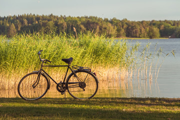 Beautiful landscape with lake. Swedish nature. Calm sunny day. Lonely old bicycle near the lake at sunset.