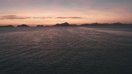 Aerial drone view of the sea surface in the light of the golden sunset. Small waves on the sea. Tranquil idyllic scene of a golden sunset over the sea with reflection.