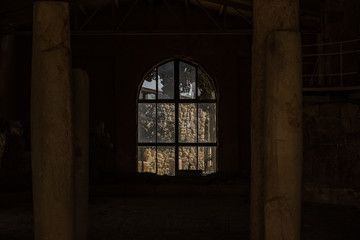 ruined abandoned stone house building inside with symmetry columns and arch window frame in twilight darkness 