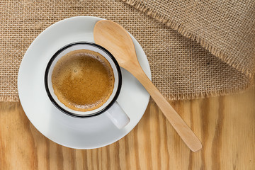 taza de café y cuchara de madera sobre tela de yute y madera