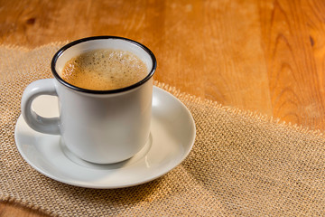 cup of coffee on jute canvas and wooden background
