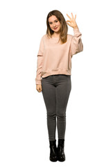 A full-length shot of a Teenager girl with pink sweater showing ok sign with fingers over isolated white background