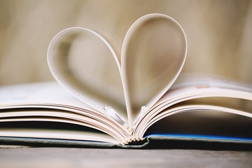 Wedding ring placed in decorate to heart shape from a open book page composition of love on wooden with blurred background. concept for valentine's day. soft focus. 