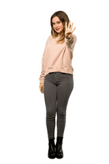 A full-length shot of a Teenager girl with pink sweater happy and counting four with fingers over isolated white background
