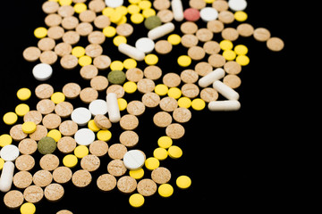 Assorted pharmaceutical medicine pills, tablets and capsules on black background. Creative idea. Drugs. Sad. Die. Illness.