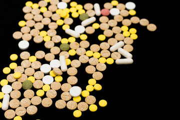 Assorted pharmaceutical medicine pills, tablets and capsules on black background. Creative idea. Drugs. Sad. Die. Illness.