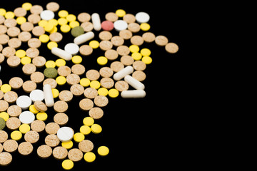 Assorted pharmaceutical medicine pills, tablets and capsules on black background. Creative idea. Drugs. Sad. Die. Illness.